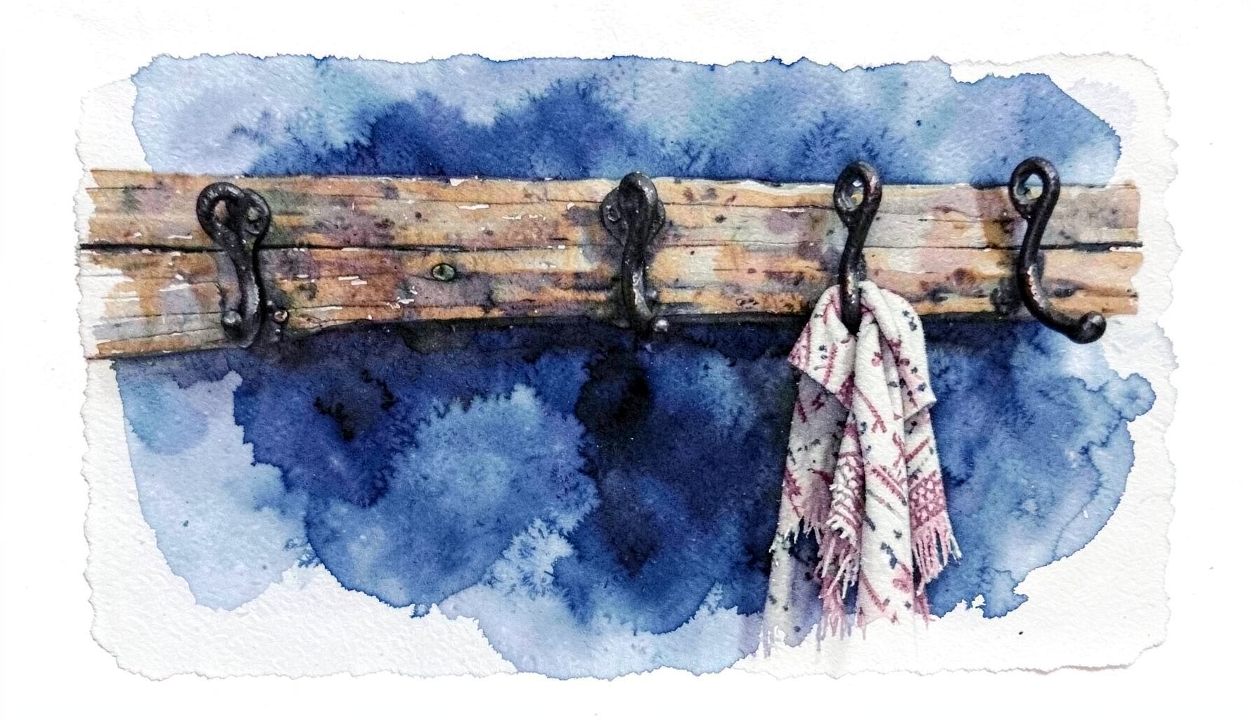 A row of dark wrought iron coat hooks mounted on a reclaimed wood board, with a woven scarf hanging from one hook