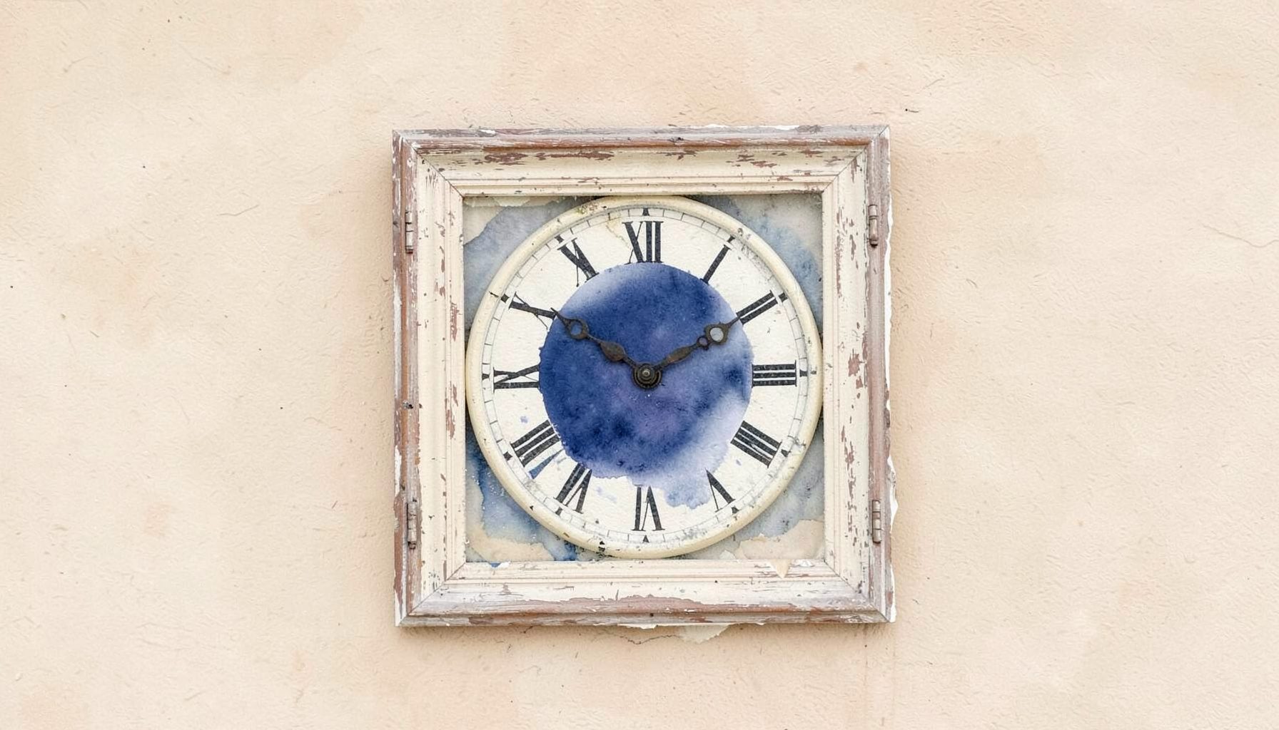 A distressed cream-colored country wall clock with Roman numerals and a weathered wooden frame, hanging against a soft beige plaster wall